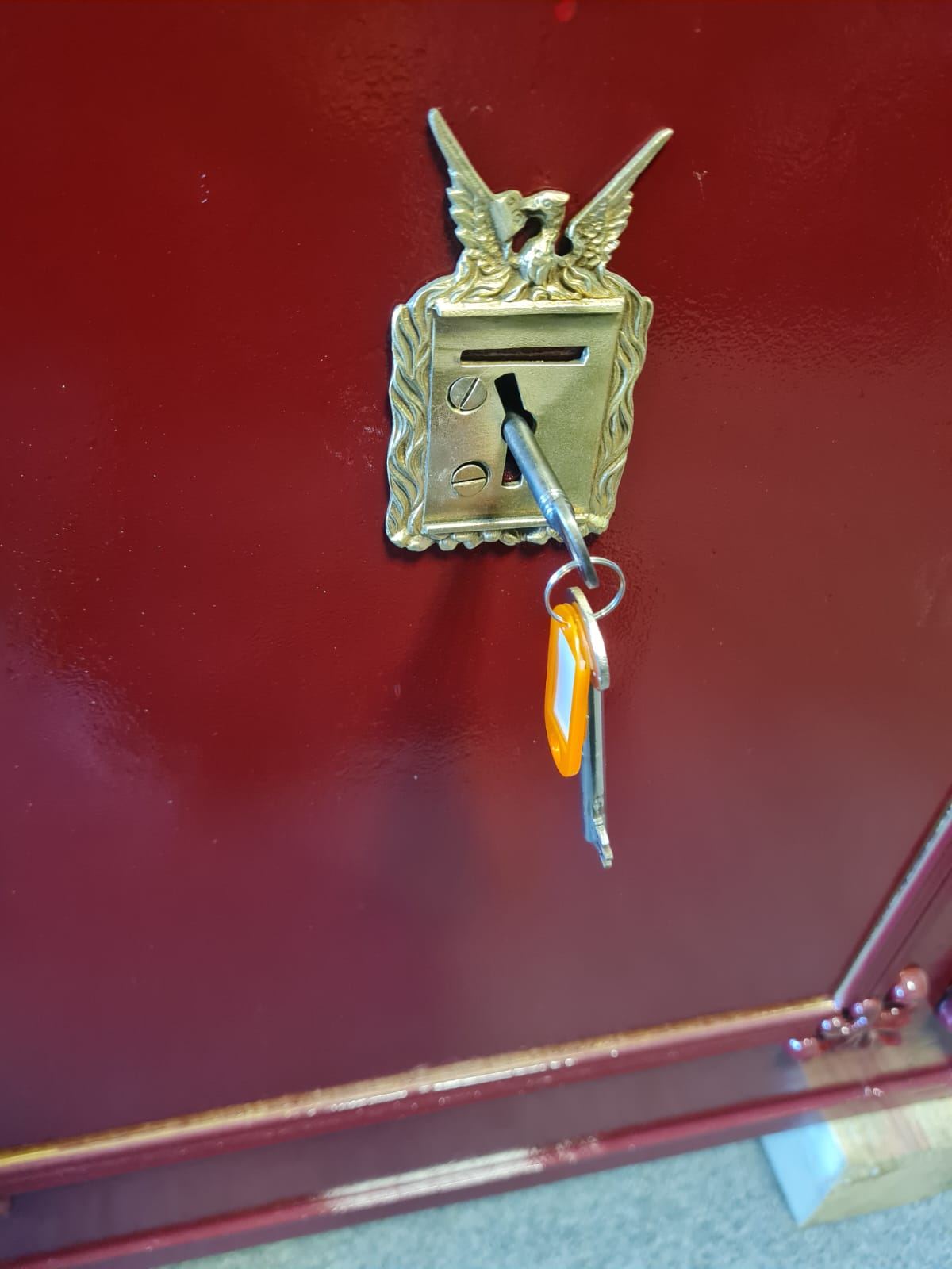 An antique safe with an ornate brass escutcheon and its working key.