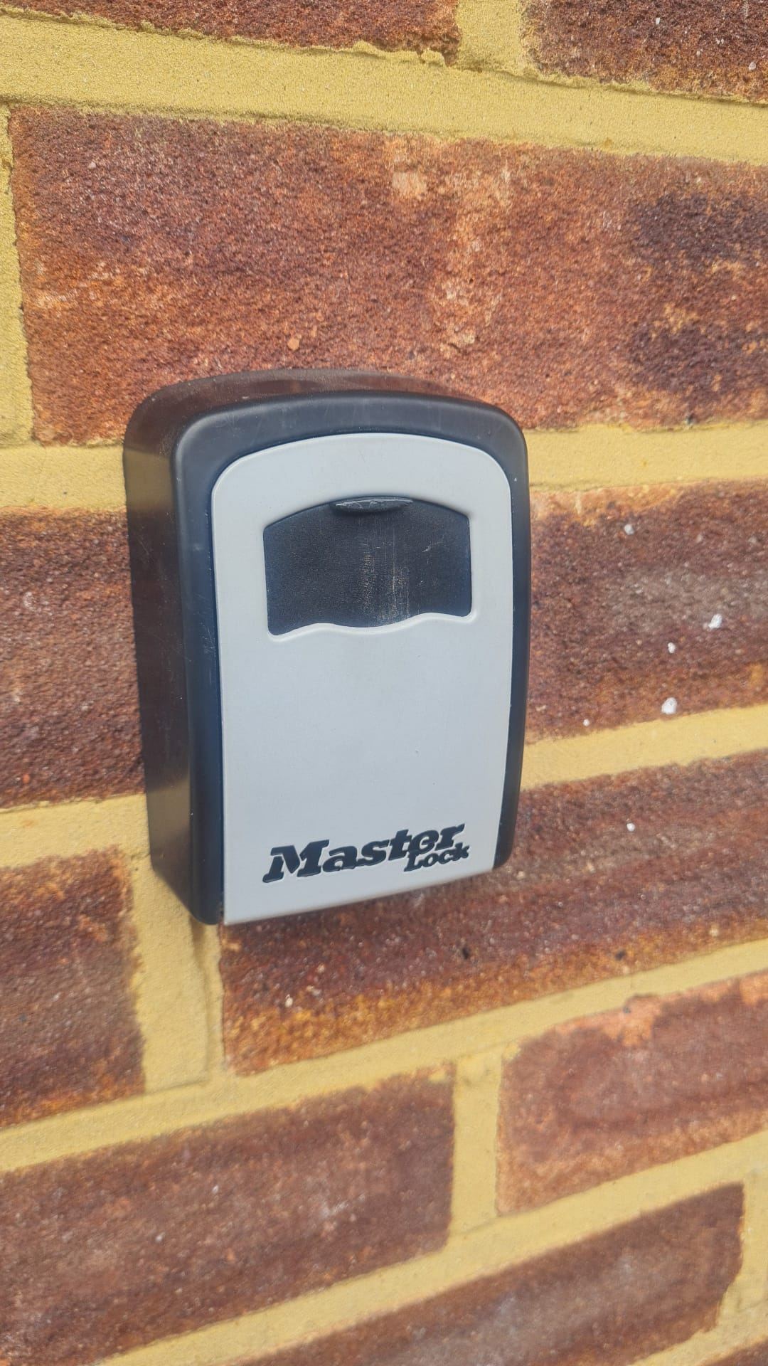 A wall-mounted key safe fitted to brickwork.