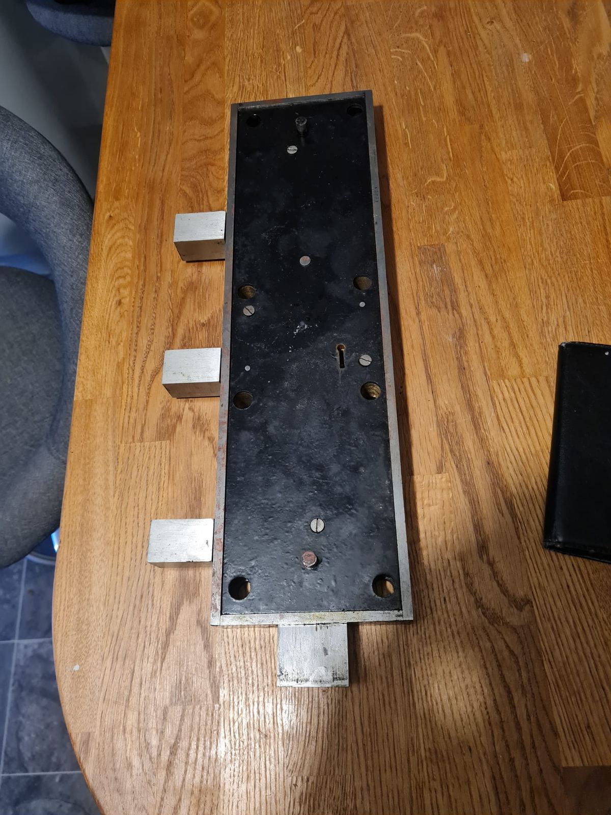 A safe lock case with its bolts extended, removed for repair on the workbench.